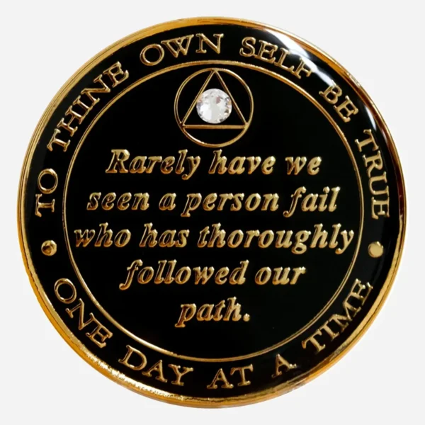 The back of a black crystal AA medallion showcasing the hand-painted Serenity Prayer in gold with a diamond accent.