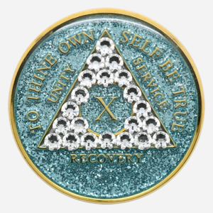 Embrace Renewal with the Crystal AA Medallion Glitter Aqua/Diamond The Crystal AA Medallion Glitter Aqua/Diamond shines as a symbol of growth and resilience on the journey of sobriety. Featuring a serene aqua background with a diamond-clear Swarovski crystal accent, each medallion is handcrafted by individuals in recovery. Available for milestones from 1 to 50 years, this medallion brings together the qualities of clarity, strength, and renewal, making it a powerful reminder of each accomplishment in recovery. Features: Material: With a genuine Swarovski crystal in diamond-clear tones set against a sparkling aqua background, this Glitter Aqua Diamond Crystal AA Medallion radiates peace and focus. Its hand-painted aqua finish is encased in a high-quality, chip-resistant resin dome to ensure lasting brilliance and durability. Front Design: The AA triangle stands proudly on the glittering aqua background, bordered by diamond-clear crystal accents around the phrase “To Thine Own Self Be True,” symbolizing authenticity and self-reflection in recovery. Roman numerals within the triangle commemorate each sobriety year, adding a personal touch that honors each milestone. Back Design: The reverse side features a single diamond-clear Swarovski crystal centered within the engraved Serenity Prayer, offering peace, clarity, and daily encouragement for the journey ahead. Dimensions: This Crystal AA Chip Glitter Aqua/Diamond measures 34mm (1.34 inches) in diameter, designed to be easily carried as a reminder of strength and resilience on the path of recovery. Durability: With a protective, scratch-resistant resin dome, the medallion’s sparkling aqua finish and crystal accents are designed to endure, providing a reliable token that reflects the steady commitment to sobriety. Benefits: Symbolism: The aqua glitter background and diamond-clear crystals represent renewal, clarity, and peace. This medallion embodies the growth and serenity that sobriety brings, encouraging each person to continue forward with strength and resolve. Personalization: Roman numerals from 1 to 50 years mark each unique milestone, creating a personal connection to each year in recovery and serving as an enduring reminder of dedication and perseverance. Gifting: Arriving in a soft velour pouch, this medallion is a heartfelt gift for anyone celebrating their journey in sobriety. Its thoughtful design supports and inspires each individual, reflecting the strength found through recovery and the beauty of each step forward. Order Your Crystal AA Medallion Glitter Aqua/Diamond Today Celebrate your journey with the Crystal AA Medallion Glitter Aqua/Diamond. Order today to enjoy fast, free shipping on all medallions, ensuring that this special token arrives in time to recognize your achievements or to encourage someone close to you. Complete the Gift with: Key Chain Holders Keep your medallion close with one of our premium Key Chain Holders, designed for both style and security on the go. Sober Greeting Cards Add a personal message of encouragement with one of our Sober Greeting Cards, ideal for celebrating each meaningful milestone. Book Covers with Chip Holders Protect your medallion and recovery literature with one of our elegant Book Covers with Chip Holders, providing accessibility and support throughout your journey.